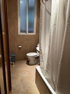 y baño con aseo y cortina de ducha. en Hostal “ INFANTAS”, en Madrid