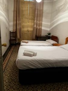 Habitación de hotel con 3 camas y toallas. en Hostal “ INFANTAS”, en Madrid