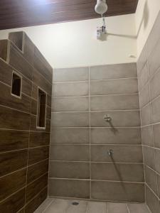 ein Bad mit einer Dusche und Holzwänden in der Unterkunft Alojamiento entero 1 km Juan Santamaría Airport in Alajuela