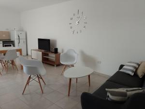 sala de estar con sofá, sillas y reloj en la pared en Alojamientos Litoral - 3 B en Gualeguaychú