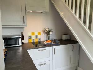 a kitchen with white cabinets and a microwave at Pass the Keys Superb space in the idyllic village of Loppington in Shrewsbury