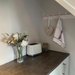 a kitchen counter with a vase of flowers and a toaster at Pass the Keys Superb space in the idyllic village of Loppington in Shrewsbury