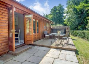 a wooden cabin with a patio with a table at Ford Farm Lodges in Aston Ingham