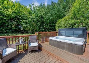 a hot tub on a deck with a table and chairs at Ford Farm Lodges in Aston Ingham