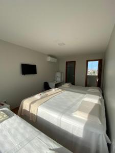 a bedroom with two beds and a tv on the wall at Pousada Ritec in Linhares
