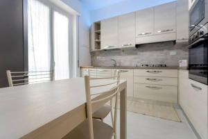 a kitchen with white cabinets and a table with chairs at La reggia del mar - Genova Sturla, mare e Gaslini in Genova +3 photos