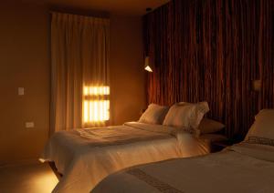 two beds in a hotel room with a window at Hotel Scappata in Progreso