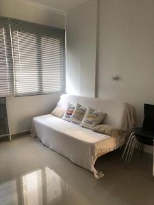 een wit bed in een kamer met een raam bij Apartamento encantador no Gonzaguinha! Todo Reformado!! Completo! in São Vicente