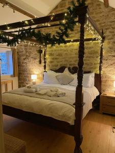 a bedroom with a canopy bed with christmas lights at Norburton Hall Cottages in Bridport