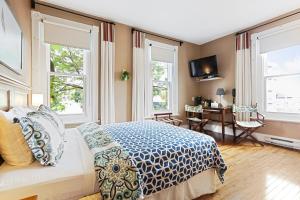 a bedroom with a bed and a desk and windows at Auberge Château Des Tourelles - Par Aneyro in Quebec City