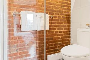 a bathroom with a toilet and a brick wall at Chateau Des Tourelles in Quebec City
