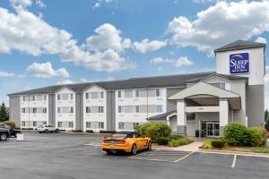 un immeuble de bureaux avec une voiture orange garée sur un parking dans l'établissement Sleep Inn & Suites Allendale, à Allendale