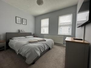 a bedroom with a large bed and two windows at Cosy, 2 Bedroom Cottage in Guisborough Town Centre in Guisborough