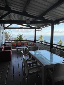 eine Terrasse mit einem Tisch, Stühlen und Meerblick in der Unterkunft Hébergement tout équipé et surveillance H24 in Koungou