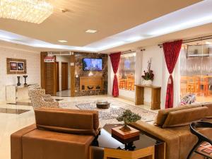 a living room with a couch and a tv at Goldmen Business Hotel in Cianorte