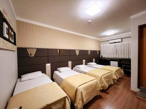 a group of four beds in a room at Paraná Comfort Hotel in Cianorte