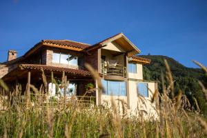 a house on a hill with tall grass at El Cerezo Casa de campo in Tópaga