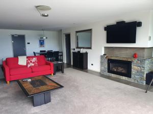 a living room with a red couch and a fireplace at Downtown Queenstown Apartment in Queenstown