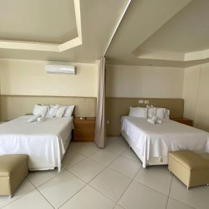 a bedroom with two beds with white sheets at Hotel Monte Rei in Salvador