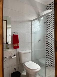 a white bathroom with a toilet and a shower at Guarujá Praia de Pernambuco in Guarujá