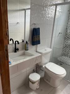 a white bathroom with a toilet and a sink at Guarujá Praia de Pernambuco in Guarujá