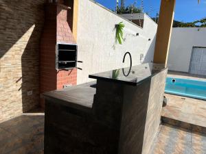 a outdoor kitchen with a counter and a swimming pool at Guarujá Praia de Pernambuco in Guarujá