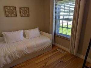 1 dormitorio con cama blanca y ventana en Comfy Champaign 3 Bedroom House, en Champaign