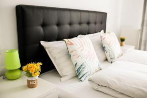 a bed with white pillows and a green vase with flowers at Modern Condo with parking, Sibiu in Sibiu