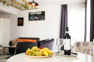 a table with a plate of fruit and a bottle of wine at Modern Condo with parking, Sibiu in Sibiu