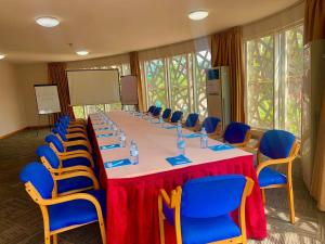 sala konferencyjna z długim stołem i niebieskimi krzesłami w obiekcie Arcadia Suites - Kampala w mieście Kampala