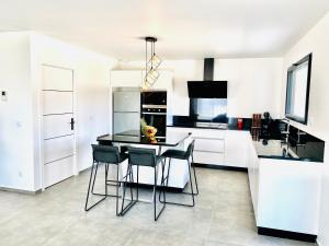 a white kitchen with a table and chairs in it at La Contemporaine in Brax