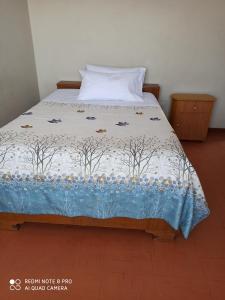 Una cama con una colcha con árboles. en Hostal Killaymi, en Arequipa