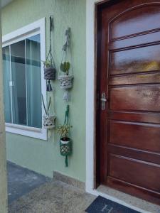 a wooden door with potted plants and a window at Triplex 3 quartos a 100 metros de Costa Azul in Rio das Ostras