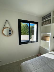 een slaapkamer met een bed, een spiegel en een raam bij STUDIO in res. LES CYCLISTES in Malaucène