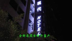 um sinal que é iluminado em azul e verde em Modern Plaza Hotel em Kaohsiung