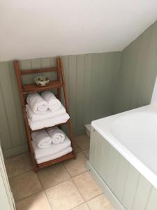 a bathroom with a rack of towels and a bath tub at Cosy Arts & Crafts Cottage with stunning views in Brecon