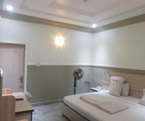 1 dormitorio con 1 cama y escritorio con ventilador en Haven Suites, Ikenegbu, en Owerri