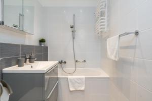 biała łazienka z umywalką i prysznicem w obiekcie Apartament Turkusowa- z widokiem na korony drzew w Poznaniu