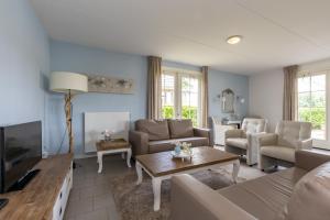 een woonkamer met een bank en een tv bij Villa WaterGeluk ҉ in Susteren