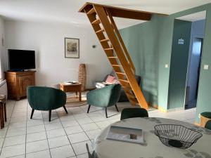 una sala de estar con sillas verdes y una escalera en Maison de village avec jardin 15mn des plages, wifi, 2 chambres, jardin, en Hesdin-lʼAbbé