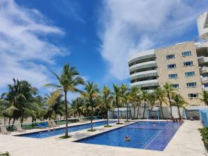 a swimming pool with palm trees in front of a building at Hermoso apartamento en la playa in Cartagena de Indias