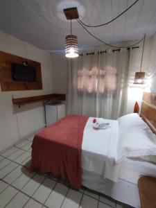 a bedroom with a bed and a tv in it at Pousada Mar e Sol in Pipa