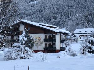 a building covered in snow with trees and mountains at Pension Gertraud in Bad Kleinkirchheim