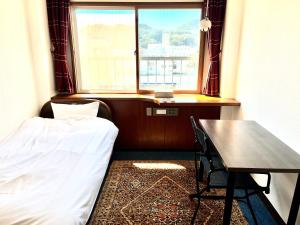 a bedroom with a bed and a table and a window at MAGURO BLDG チェックインはWhyKumano in Nachikatsuura