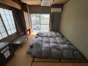 two beds in a room with a large window at MAGURO BLDG チェックインはWhyKumano in Nachikatsuura