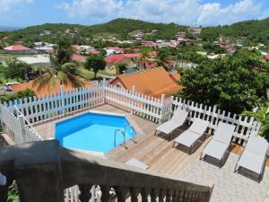 a balcony with a pool and chairs and a fence at TERRE DE BAS :L'île merveilleuse in Terre-de-Bas