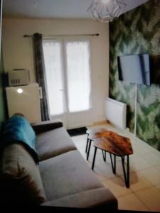 Una sala de estar con un sofá y una mesa de café. en Bel appartement avec jardin à 50m des plages du debarquement, en Bernières-sur-Mer