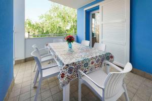 a table with white chairs and a vase of flowers on a balcony at Villa Boer in Bibione
