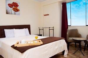 Una habitación de hotel con una cama con una bandeja de comida. en COSMOPOLITAN INN, en Ventanilla