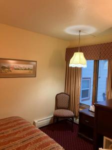 um quarto de hotel com uma cama e uma cadeira e uma janela em Hotel Seward em Seward